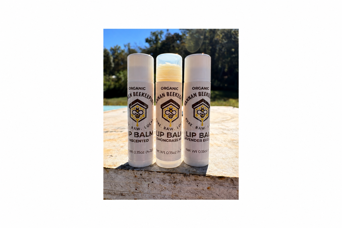 Three Hannan Beekeeping lip balm tubes at the apiary, framed with generous margins